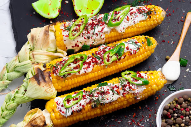 istock Grilled corn with cream sauce, spices, jalapeno on the black stone tile. 1026317384