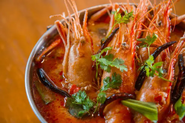 Photo of Traditional thai cuisine, Tom yum goong, Spicy shrimp soup on wooden background