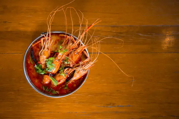 Photo of Traditional thai cuisine, Tom yum goong, Spicy shrimp soup on wooden background