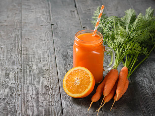 istock A mug of fresh carrot smoothie with cocktail straw, carrots and oranges on a rustic table. 1026347626