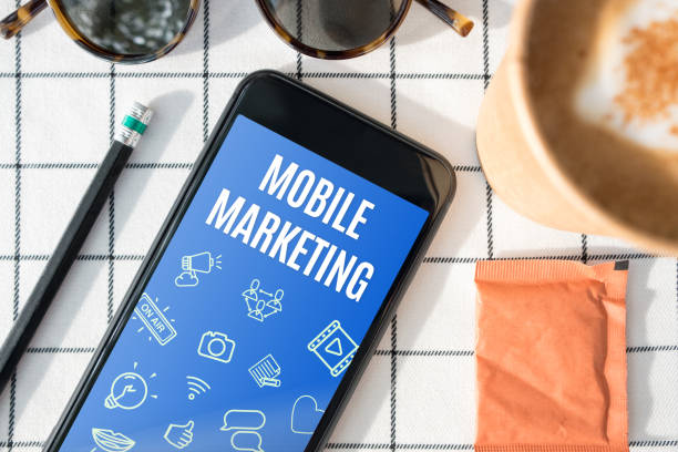 istock top view mobile marketing feature on mobile screen with coffee cup,sunglasses,pencil on white table cloth.digital advertising. 1026357520