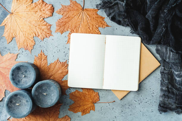 istock Autumn flat lay composition on a grey concrete background. Maple leaves, the open notebook with empty sheets, black aromatic candles and warm scarf. Mockup, top view. 1026381222