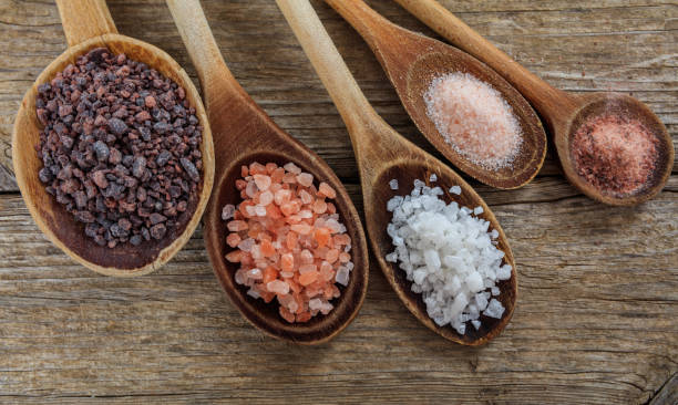 Variety of salts in spoons Variety of salts in wooden spoons salt seasoning stock pictures, royalty-free photos & images