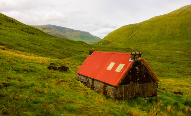 A red roofed barn in the wilderness of the Scottish highlands.