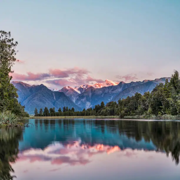 Lake Matheson at sunset with snow covered Mount Cook, New Zealand's highest mountain.