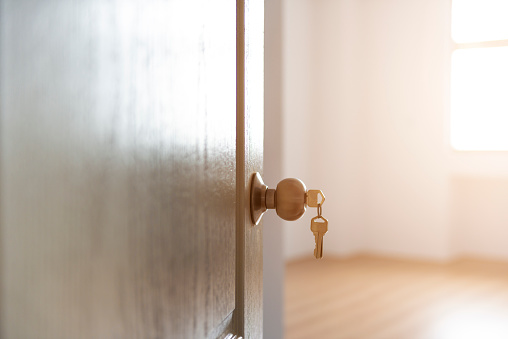 Close-up shot of woman's hand using key to unlock doors. Grey modern design house doors, selective focus.