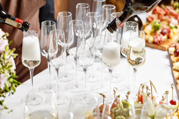 istock Bartender pouring champagne or wine into wine glasses on the table in restaurant. solemn wedding ceremony or happy new year banquet 1026423620