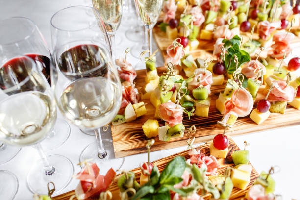 ¡feliz año nuevo solemne banquete. lote de copas de champagne o vino en la mesa en el restaurante. mesa de buffet con un montón de deliciosos bocadillos. canapés, bruschetta y postres poco a bordo de la placa de madera - bruschetta buffet party food fotografías e imágenes de stock