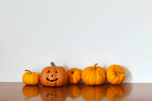 istock Orange halloween pumpkin on wooden table White wall 1026434656