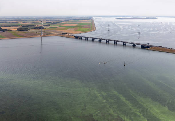 vista aérea holandesa paisaje con puente, turbina de viento y algas - netherlands dyke polder aerial view fotografías e imágenes de stock