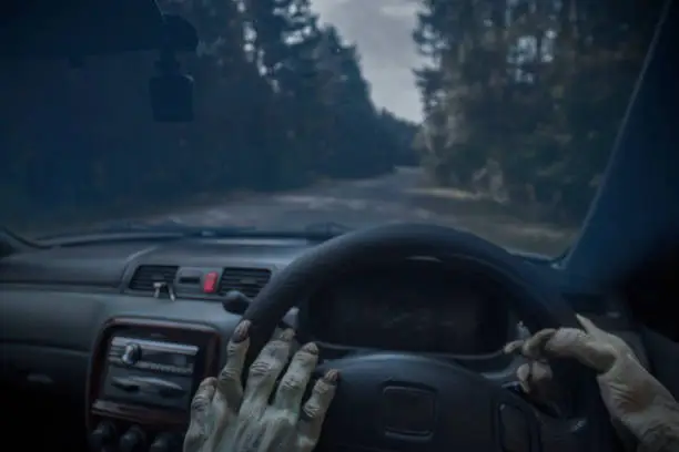 Photo of The hands of zombies and the steering wheel of a car