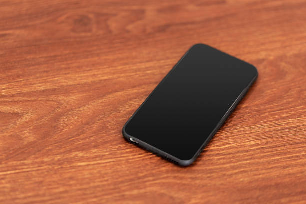 istock Mobile phone with blank screen on wooden table background. 1026456564