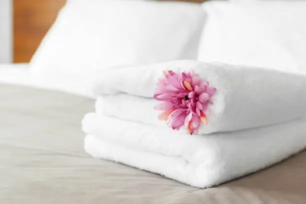 Photo of towels and flower on bed in hotel room