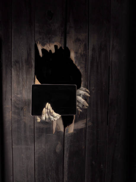 istock Zombie hand through hole cracked in rustic wood.Halloween theme 1026458722