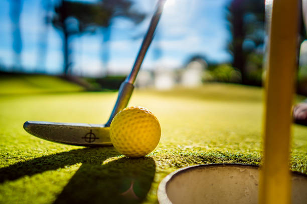 istock Mini Golf yellow ball with a bat near the hole at sunset 1026472948
