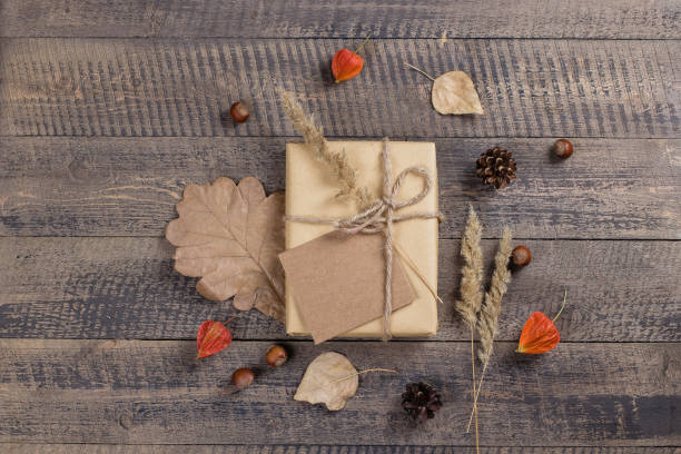 istock Autumn composition. Gift or Present box with empty card, autumn leaves, physalis, pine cones on brown rustic wooden background. Flat lay, top view, copy space 1026480772