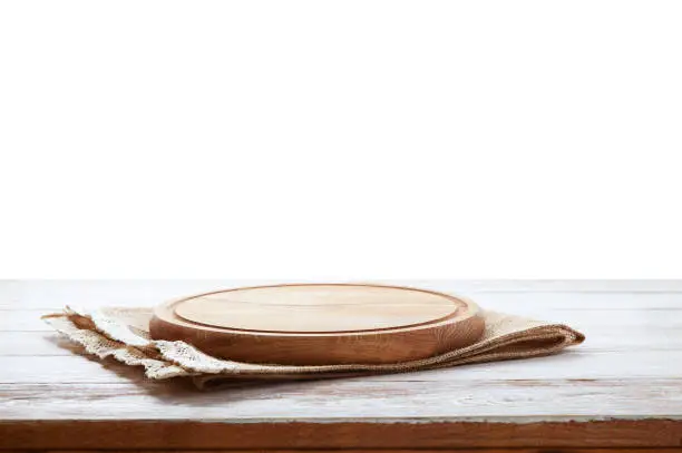 Photo of Napkin and board for pizza on wooden desk. Canvas, dish towels on white wooden table background top view mock up. Selective focus.