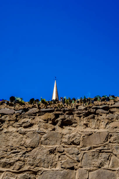 Anti climb wall and church spire Stone wall with anti climb broken glass with church spire against clear blue sky sentinel spire stock pictures, royalty-free photos & images
