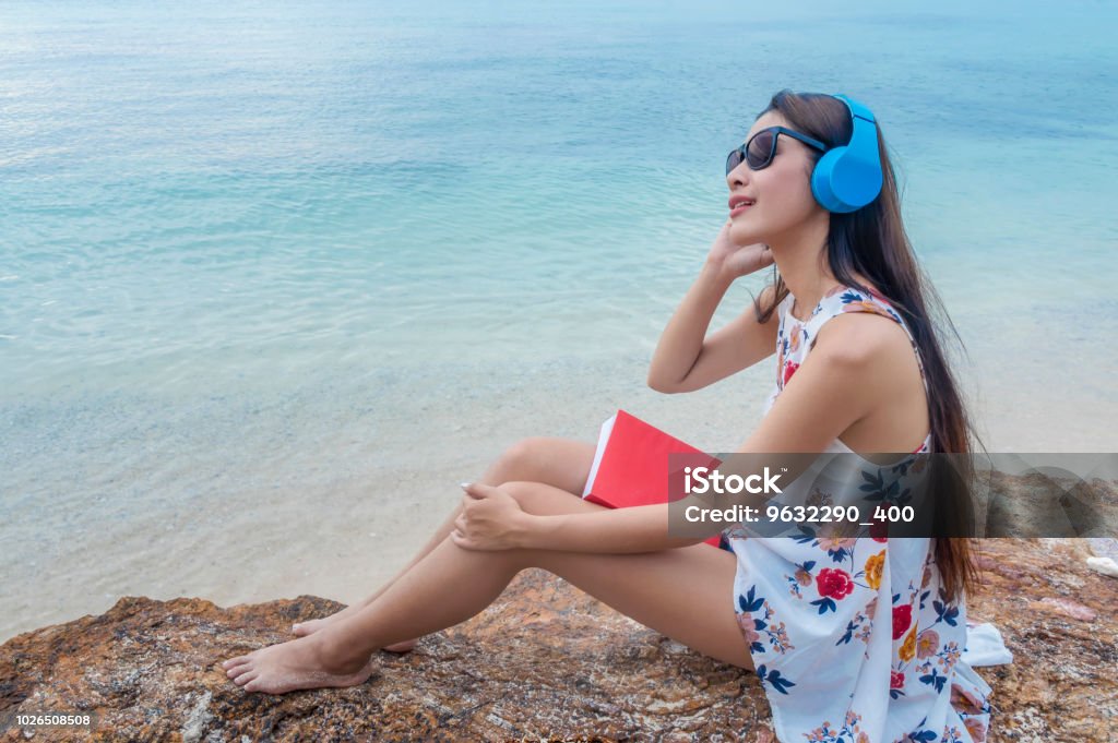 Beautiful Smiling Girl Listening To Music And Reading A Book On ...