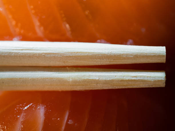 Disposable bamboo chopsticks and salmon sushi in background macro shot