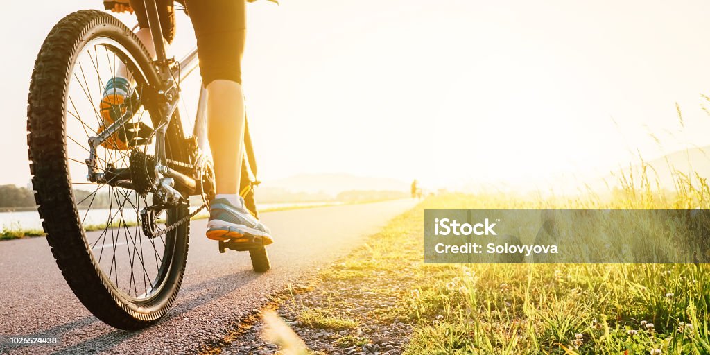 Woman feet on bycikle pedal in sunset light Cycling Stock Photo