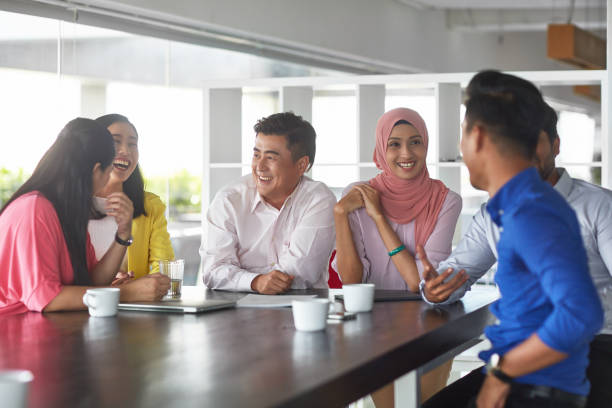 istock Friendly colleagues laughing at table in office 1026526722