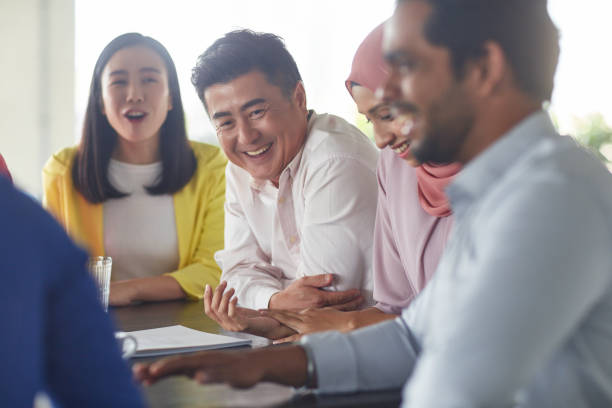 istock Smiling businessman sitting with team in office 1026528610