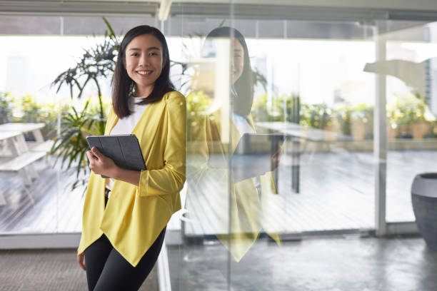 istock Businesswoman with tablet PC leaning on glass wall 1026529452