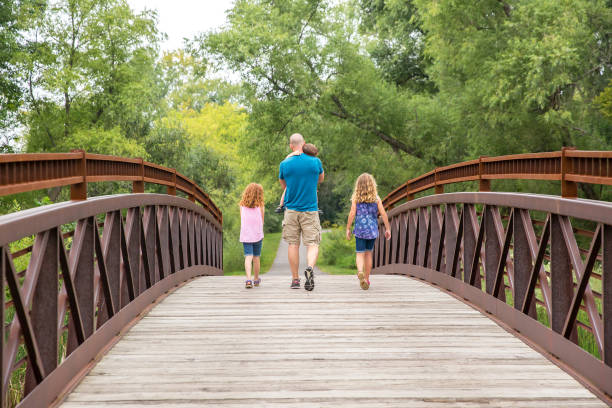 Father & Three Children Walking Across Bridge in Woods