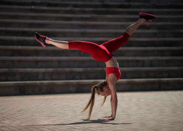 istock Young attractive woman practicing yoga outdoors. The girl performs a handstand upside down 1026545464