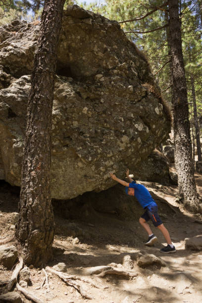istock Little boy lifting heavy rock in forest 1026551534