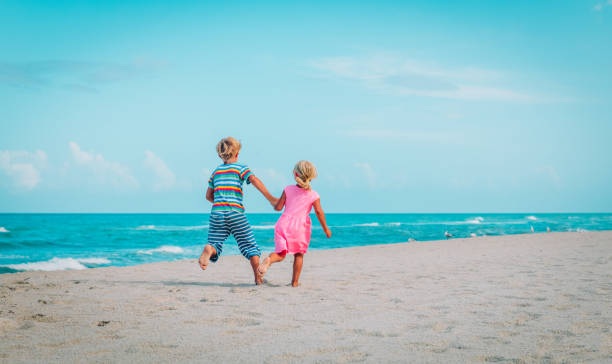 istock little boy and girl running on beach 1026555988