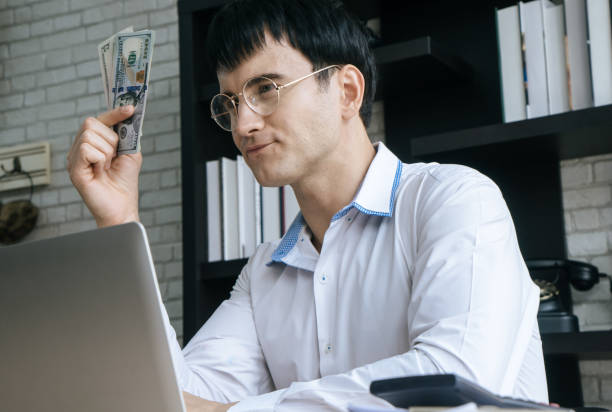 istock Business man counting dollar bill money in office 1026558608
