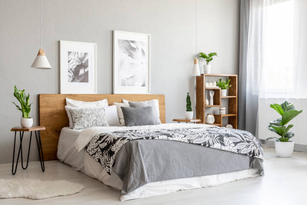 coperta fantasia su letto di legno in interni grigi della camera da letto con piante e poster. foto reale - headboard foto e immagini stock