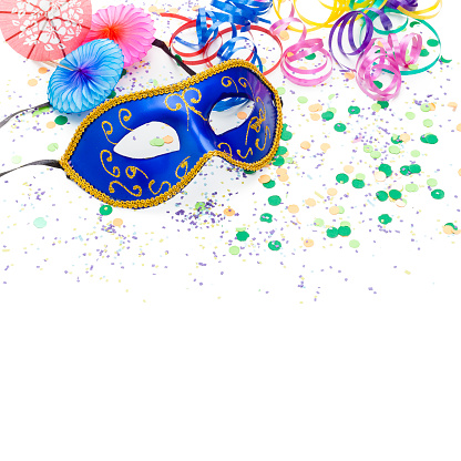 Colorful carnival or party decoration items like streamers, party umbrellas, masquerade mask, party horn blower and confetti shot on white backdrop.  The composition is at the top of a white background leaving useful copy space for text and/or logo at the bottom. High key DSRL studio photo taken with Canon EOS 5D Mk II and Canon EF 100mm f/2.8L Macro IS USM.
