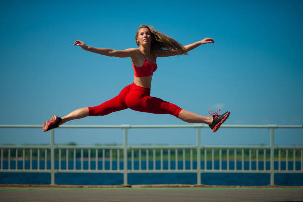 istock Young caucasian girl performs twine jumping on sky backround. 1026565696