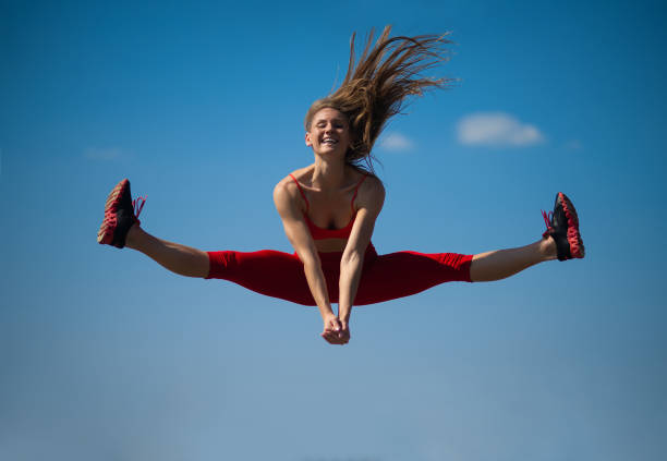 istock Young caucasian girl performs twine jumping on sky backround. 1026565882