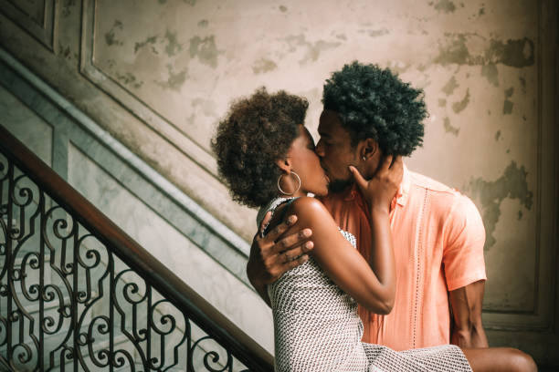 giovane coppia che si bacia sui gradini contro muro, l'avana, cuba - couple black american culture kissing foto e immagini stock