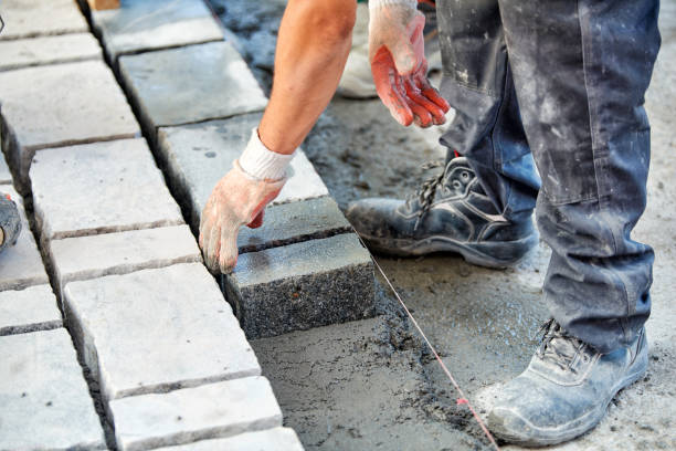 istock A workman's gloved hands use a hammer to place stone pavers. Worker creating pavement using cobblestone blocks and granite stones. 1026567328