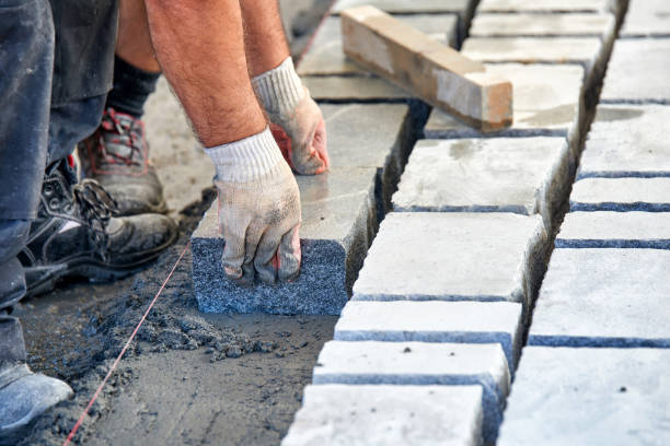 istock A workman's gloved hands use a hammer to place stone pavers. Worker creating pavement using cobblestone blocks and granite stones. 1026567476
