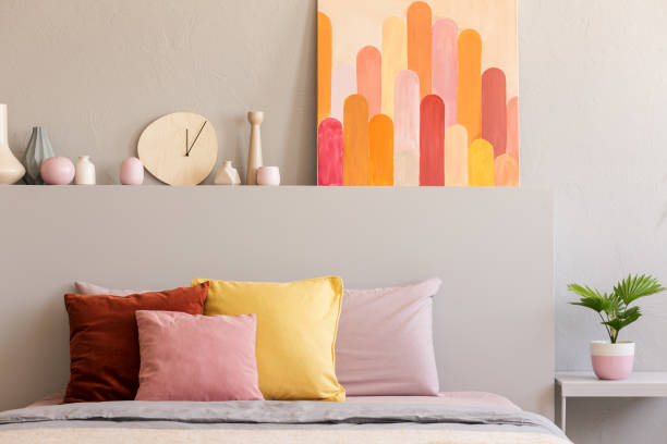 красочные подушки на кровати в сером интерьере спальни с плакатом и часами на кровати. реальное фото - decor indoors pillow bedroom стоковые фото и изображения