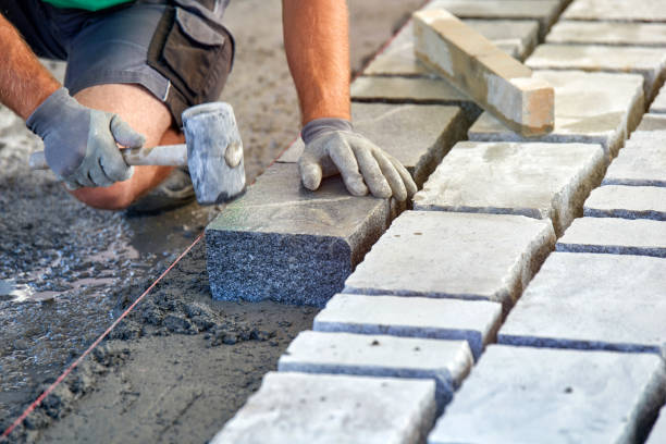 istock A workman's gloved hands use a hammer to place stone pavers. Worker creating pavement using cobblestone blocks and granite stones. 1026567534