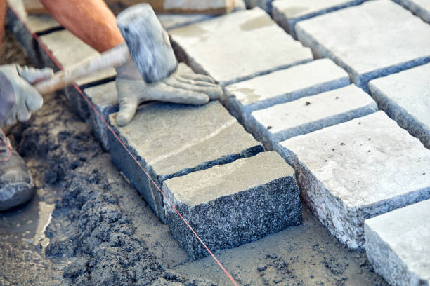istock A workman's gloved hands use a hammer to place stone pavers. Worker creating pavement using cobblestone blocks and granite stones. 1026569834