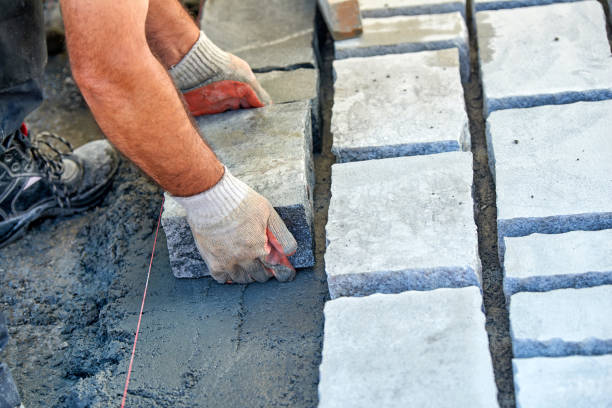 istock A workman's gloved hands use a hammer to place stone pavers. Worker creating pavement using cobblestone blocks and granite stones. 1026572038