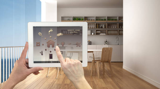istock Smart remote home control system on a digital tablet. Device with app icons. Minimalist modern panoramic kitchen in the background, architecture interior design 1026572348