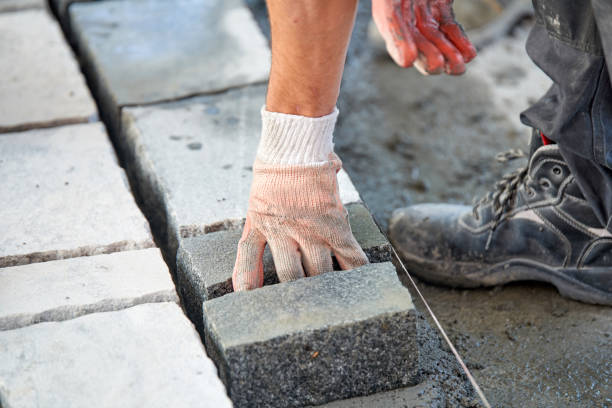 istock A workman's gloved hands use a hammer to place stone pavers. Worker creating pavement using cobblestone blocks and granite stones. 1026572438