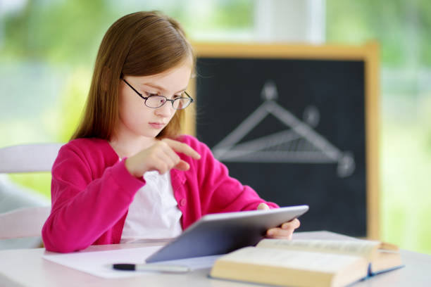 Studio shot of an unrecognizable little girl posing with a tablet in front of her face against a blue background