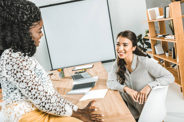istock multiethnic smiling businesswomen having conversation at workplace in office 1026576876