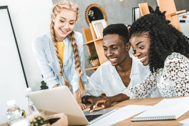istock multicultural smiling businessman and businesswomen using laptop at workplace in office 1026577310