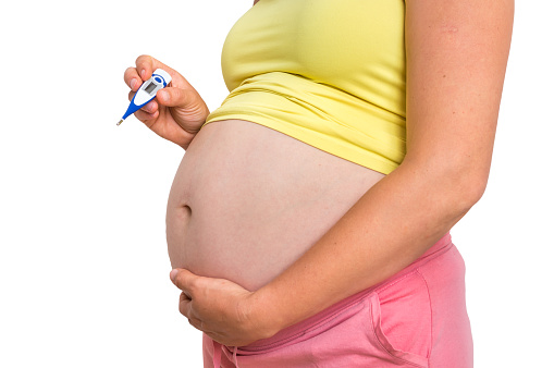 Pregnant woman with temperature is holding thermometer - cold and flu during pregnancy